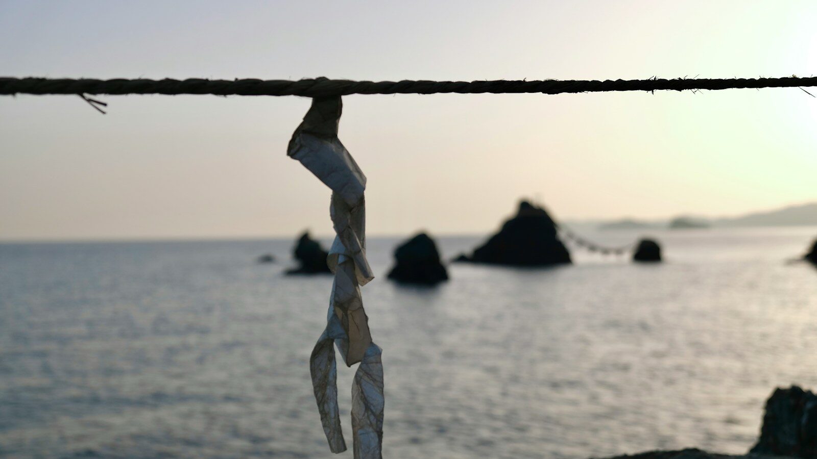 a piece of paper hanging from a rope near the ocean